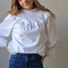 Blusa blanca con volante en el cuello y mangas