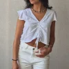 Camiseta blanca con volantes en los hombros y frunce en el pecho