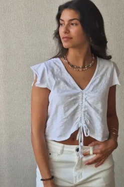 Camiseta blanca con volantes en los hombros y frunce en el pecho