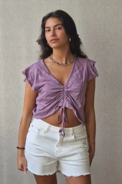 Camiseta lila con volantes en los hombros y frunce en el pecho